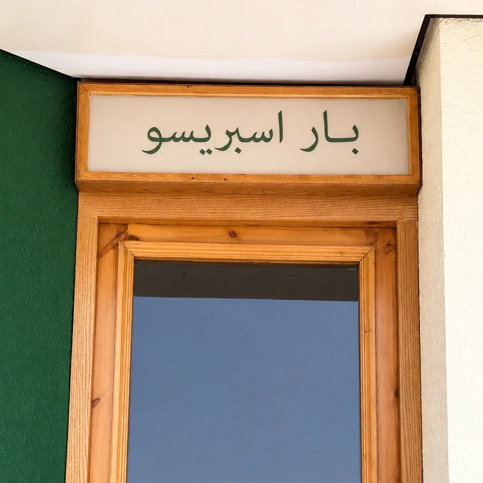 لوحة بار اسبريسو المضيئة فوق باب نثل الخشبي، بخطهم الأخضر